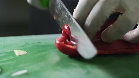 Close-up-man's-hand-slicing-red-fresh-pepper-on-a-cutting-board-with-sharp-knife