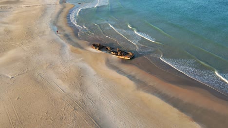 Aerial-view-of-wrecked-boat,-on-the-shoreline-,-on-the-beach-in-Moshav-Habonim-Taken-at-Habonim-beach,-israel