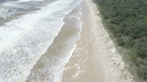 Schäumende-Wellen,-Die-Nach-Dem-Sturm-Am-Sandigen-Ufer-Des-Strandes-Angespült-Werden