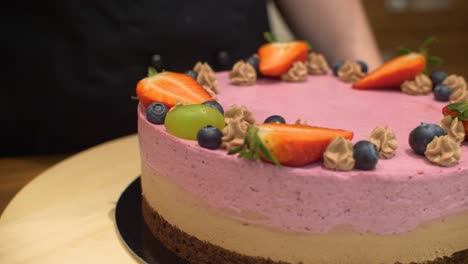 Woman-decorating-cream-cake-with-grape-fruit