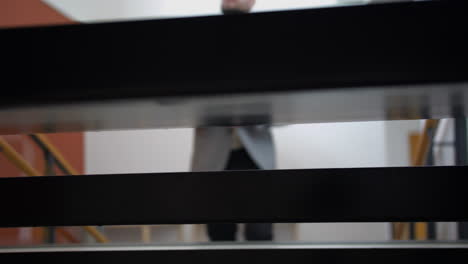 View-through-stairs-of-businessman-walking-up,-slow-motion