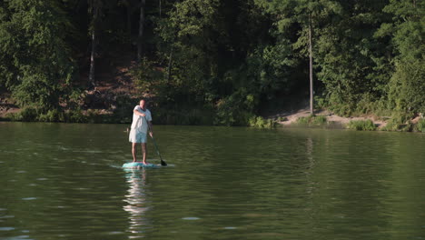 Senior-caucasian-guy-paddling-paddleboard-on-pond-or-lake,-front-wide-angle-view