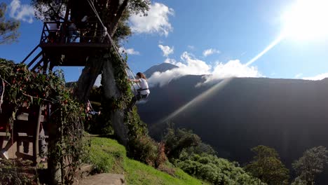 A-woman-opens-her-arms-in-happiness-while-enjoying-the-Swing-at-the-End-of-the-World-in-Baños,-Ecuador