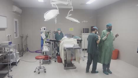 Team-of-doctors-cleaning-up-after-surgery-in-Kabul-hospital,-reveal-view