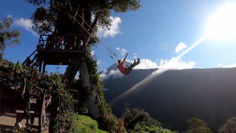A-tourist-is-having-a-great-time-in-the-the-Swing-at-the-End-of-the-World-in-Baños,-Ecuador-with-the-view-of-the-Tungurahua-Volcano