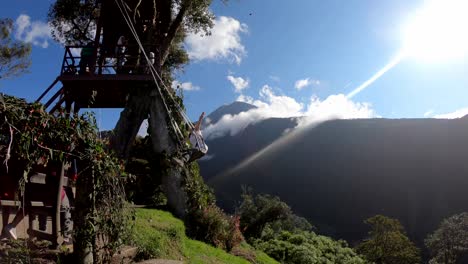 A-woman-is-opening-her-arms-while-enjoying-the-Swing-at-the-End-of-the-World-in-Baños,-Ecuador