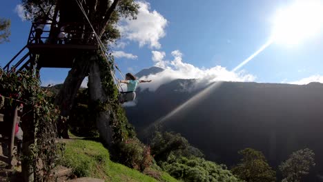 A-woman-swing-the-famous-Swing-at-the-End-of-the-World-in-Baños,-Ecuador-located-in-front-of-Tungurahua-Volcano