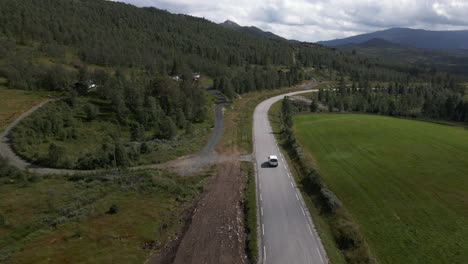 Aerial-drone-shot-of-car-driving-near-the-forest-road-in-Norway