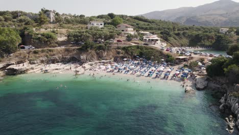 Bataria-Beach-in-Kassiopi,-Pebble-small-beach-with-crystal-clear-water,-Corfu-Island,-Aerial-Orbiting