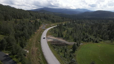 Aerial-drone-shot-of-car-driving-in-the-road-near-the-mountain-and-valley-