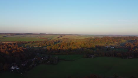 Herbstluftaufnahme-über-Die-Englische-Landschaft-Mit-Einem-Kleinen-Malerischen-Dorf,-Während-Die-Sonne-über-Den-Feldern-Untergeht---Drohnenaufnahme-In-Dorset,-Großbritannien