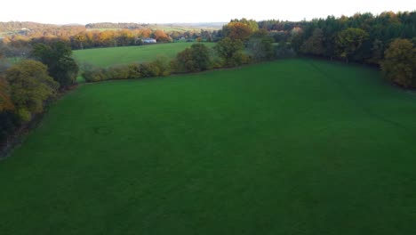 Sideways-Drone-Shot-of-English-Field-with-Church-and-Rich-Countryside-Estate-in-Background---Aerial-4K