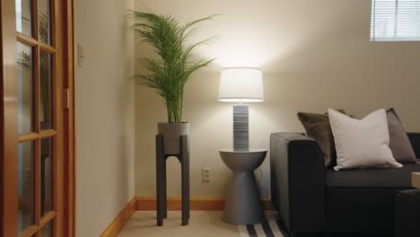 Grüne-Pflanze-Und-Eine-Moderne-Lampe-Auf-Einem-Beistelltisch-Neben-Einem-Sofa-In-Einem-Familienzimmer