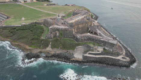 Old-And-Historic-El-Morro-Citadel-With-Ocean-Waves-Crashing-On-The-Rocky-Shoreline-In-San-Juan,-Puerto-Rico