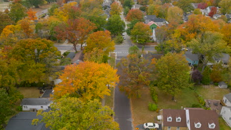 Aerial-following-a-car-as-it-drives-down-a-street-in-a-nice-neighborhood-in-Autumn-on-a-pretty-day