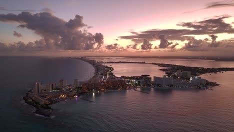 Aerial-overview-of-seaside-resorts-and-beaches,-sundown-in-Hotel-zone-of-Cancun,-Mexico---rising,-drone-shot