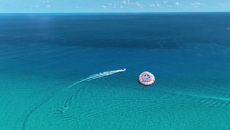 Aerial-view-following-people-parasailing-on-the-coast-of-sunny-Cancun,-Mexico