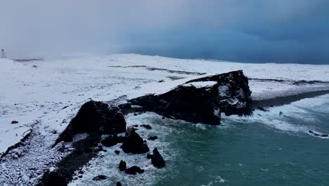 Ocean-Waves-Splashing-On-Tuff-Rock-Covered-With-Snow-In-Winter