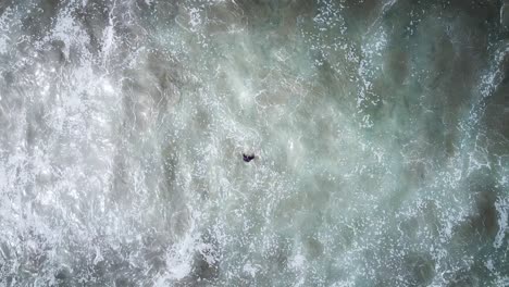 Luftaufnahme-Von-Oben-Nach-Unten-Des-Surfers,-Der-Wasser-Tritt,-Während-Sich-Große-Wellen-Nähern