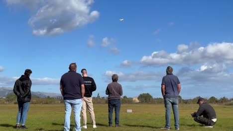 Group-of-people-watching-drone-landing-on-windy-day-at-aerodrome