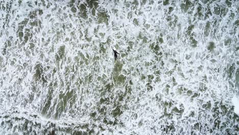 Aerial-top-down-view-of-surfer-treading-in-large-waves