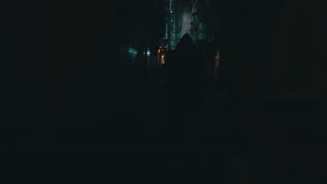 A-cinematic-shot-of-a-hooded-figure-running-behind-a-girl-in-a-small-dark-eerie-and-dirty-street-during-the-night