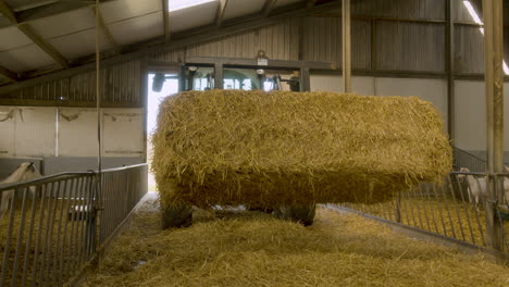 A-tractor-pulling-into-a-barn-with-a-massive-block-of-hay