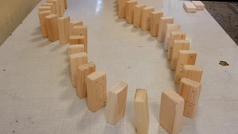Wooden-domino-pieces-falling-in-ripple-effect-on-a-table