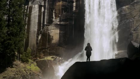 Silhouette-of-a-girl-walking-in-front-of-waterfall