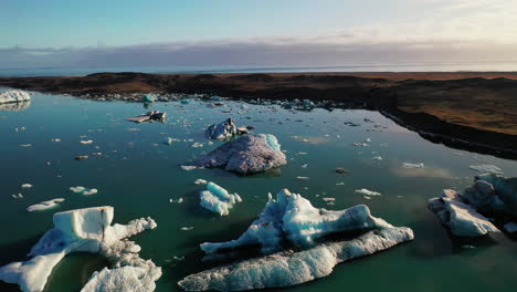 Fliegen-über-Die-Eisberge-Des-Jokusarlon-Gletschersees-Im-Südosten-Islands-An-Einem-Klaren,-Sonnigen-Tag---Luftaufnahme