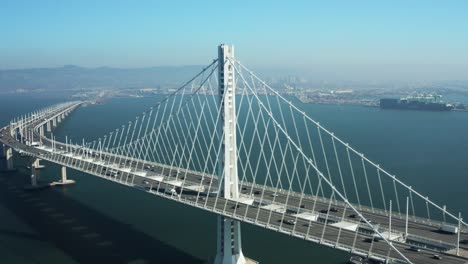 Aerial-Shot-of-Bay-Bridge-pulling-back-with-Oakland-in-background-as-cars-commute,-San-Francisco-California
