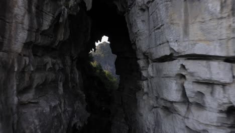 Amazing-stone-natural-archway-in-karst-mountain,-aerial-pull-back-reveal
