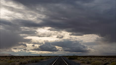 Heavy-clouds-drifting-over-train-tracks-in-desert,-Time-Lapse