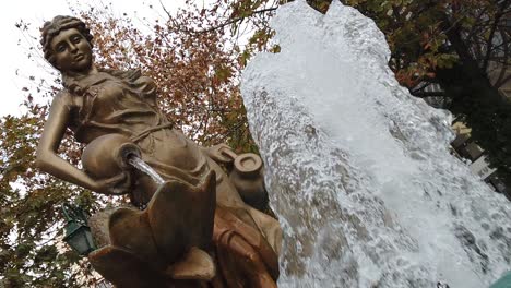 Eine-Bronzene-Frauenstatue-Hinter-Einem-Brunnen