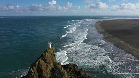 Flight-backwards-along-Whatipu-beach-and-over-Lighthouse-rock,-New-Zealand