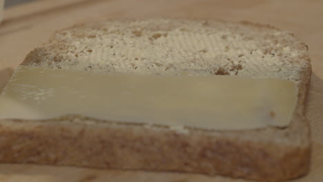 Käsescheiben-Werden-Langsam-Auf-Eine-Scheibe-Vollkornbrot-Mit-Butter-Gelegt-Und-Ergeben-Ein-Köstliches-Sandwich