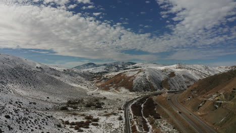 Aerial-view-of-cars-driving-on-highway-in-snowy-California-mountains