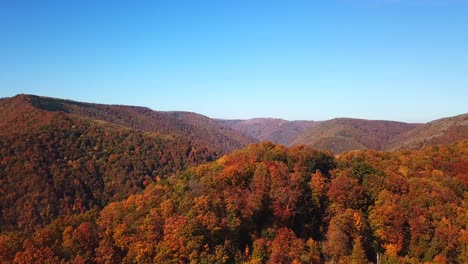 Forward-aerial-shot-over-lake-Tarnita,-Romania,-surrounded-by-colorful-autumn-trees
