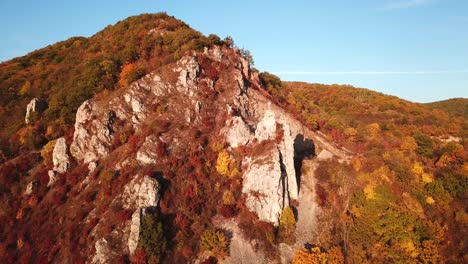 Forward-aerial-shot-towards-a-cross-on-top-of-a-mount-covered-in-autumn-trees