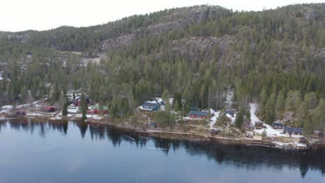 Montaña-Con-Lago-Natural-Forestal-Y-Casas-Pequeñas-Filmadas-Con-Drones-En-Invierno-En-Noruega
