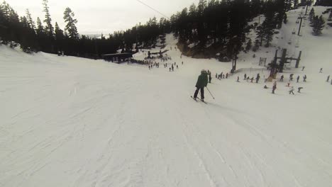 POV-snowboarder-following-a-skier-in-a-green-jacket-as-he-makes-his-way-to-the-lift-lines