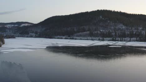 Frozen-lake-on-a-mountain-with-a-forest-on-it-in-winter