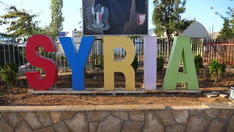 Dolly-in-to-colorful-Syria-sign-marking-the-route-into-Damascus