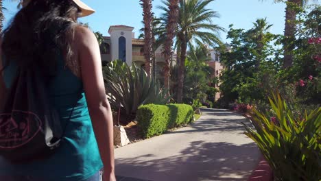Back-of-Lonely-Female-Walking-on-Trail-in-Tropical-Garden-of-Luxury-Hotel,-Static-Shot
