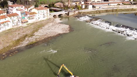 Water-escavator-working-inside-Arno-river-near-Sieci-town,-Pontassieve,-to-avoid-another-Florence-disaster-flood-afer-latest-November-rainy-long-season