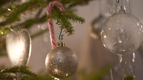 Adornos-Navideños-Transparentes-Colgando-En-Un-árbol-De-Navidad-Real,-Cerrar-La-Bandeja-A-La-Izquierda