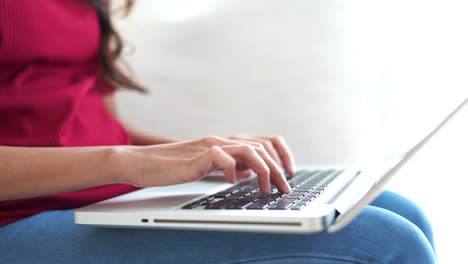 Close-up-of-a-woman-typing-on-her-laptop-balancing-on-her-lap