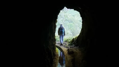 Man-walking-out-of-small-tunnel-under-mountain-in-Madeira-Island