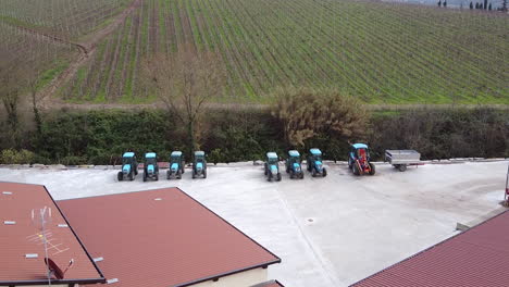 Wine-farm-with-tractors-and-vineyards-in-Tuscany-Italy,-aerial