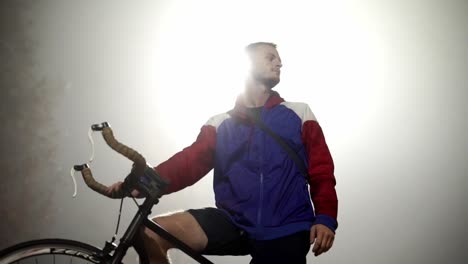 Athletischer-Mann-Auf-Dem-Fahrrad,-Hinterleuchtet-Von-Straßenlaterne-In-Einer-Nebligen-Nacht-In-Zeitlupe